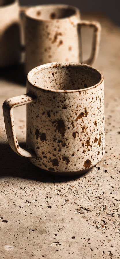 Standard Mug in speckled beige ceramic with a rustic texture and a simple handle.