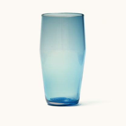 A translucent blue pint glass with a tapered shape, casting a soft shadow on a white background.
