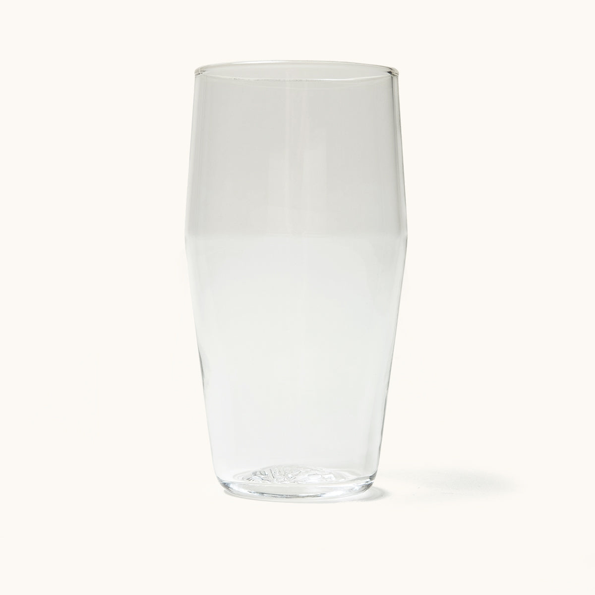 Clear standard pint glass, empty, with a subtle textured pattern on the base.