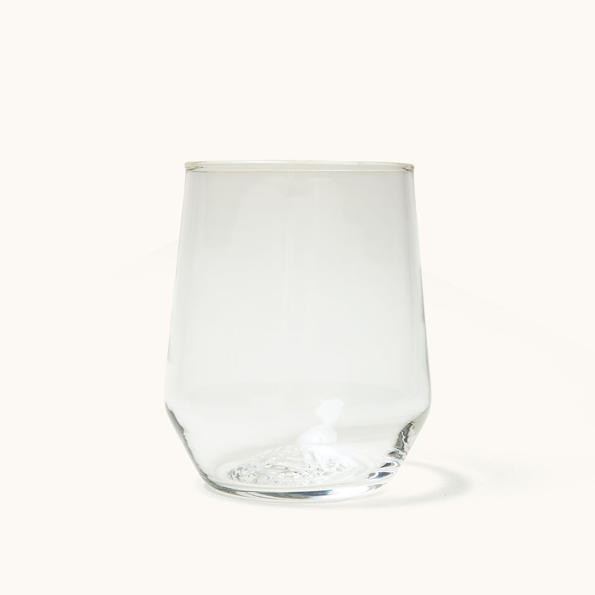 Clear, stemless wine glass with smooth, tapered sides and a subtle textured pattern at its base.