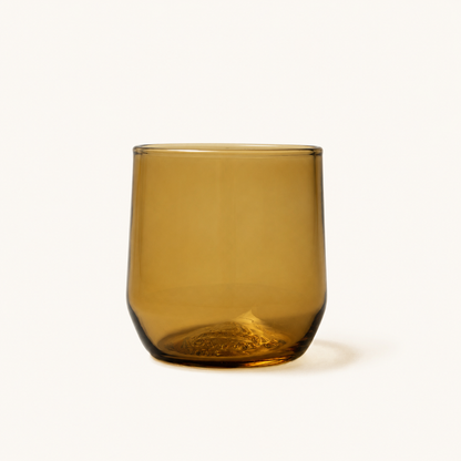 Amber-colored cocktail glass with rounded shape and embossed base, front view on white background