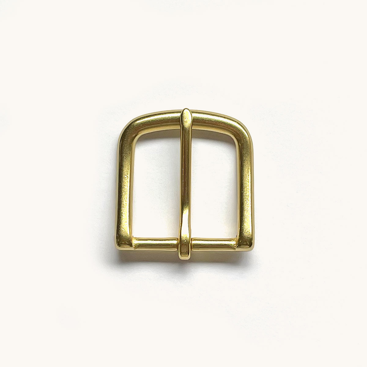 Shiny brass-toned belt buckle with a rounded rectangular frame and single prong, viewed from above.