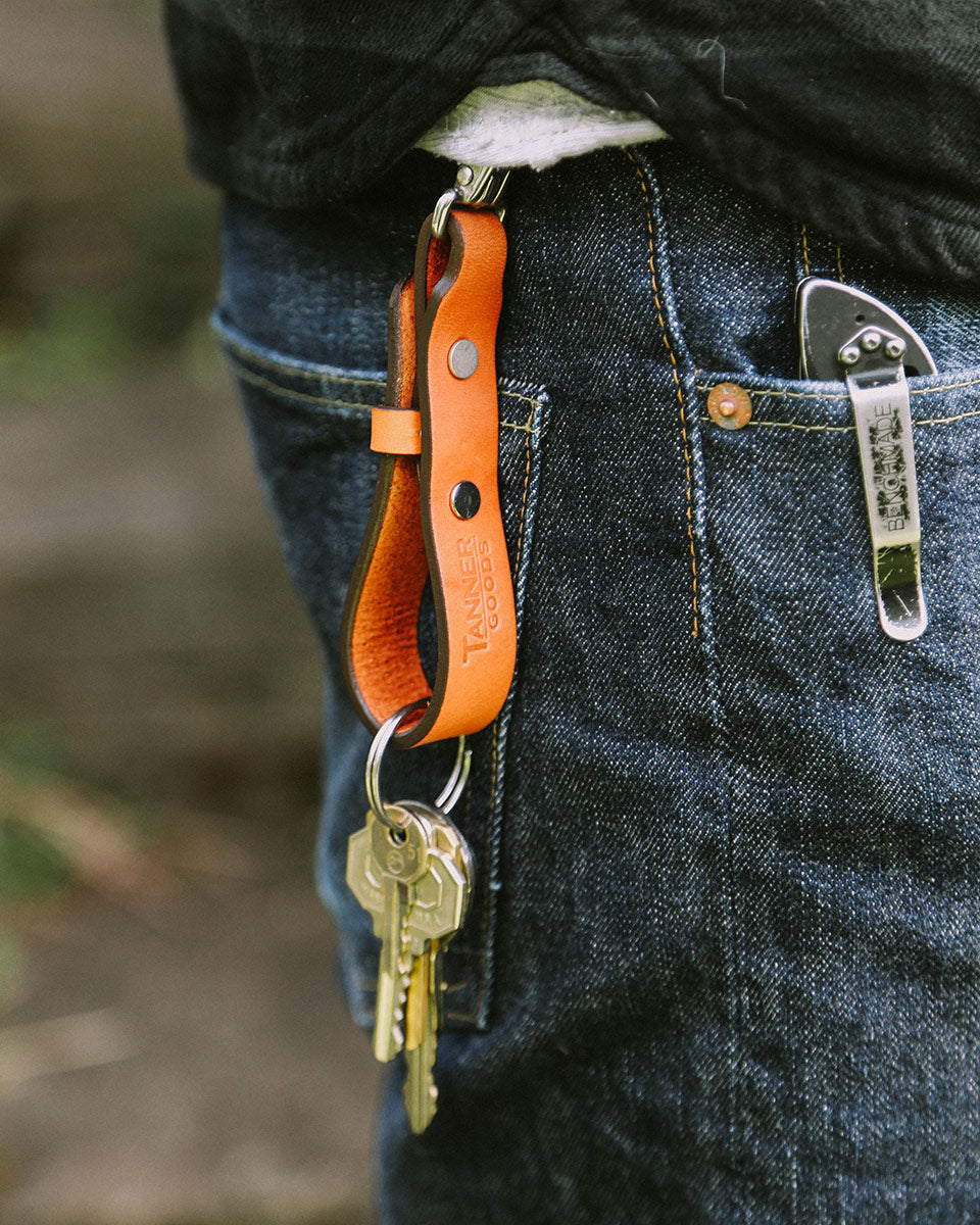 Saddle tan leather Key Lanyard by Tanner Goods, clipped to blue jeans with attached keys and a pocket knife.