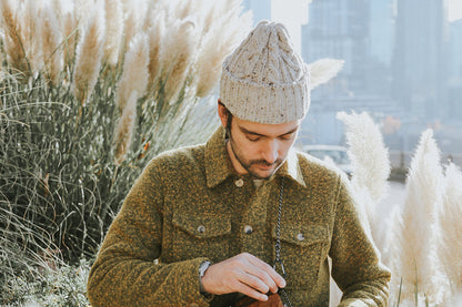 Light beige speckled cable knit cap worn by a man with an olive green textured jacket.