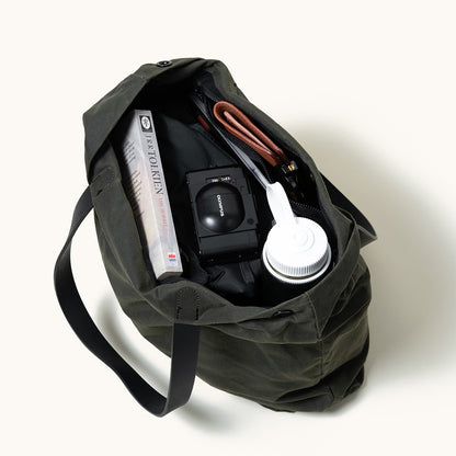 Juniper green waxed canvas Simple Tote, open with a book, camera, wallet, and water bottle inside.