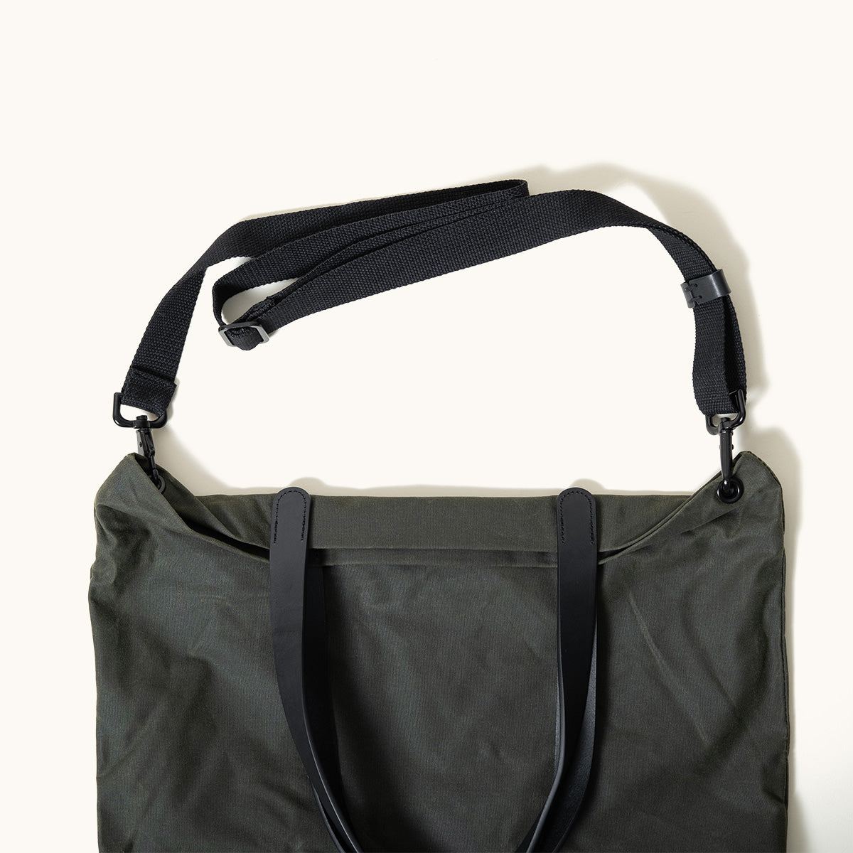 Juniper Green waxed canvas Simple Tote with black leather carry handles and an adjustable black shoulder strap, seen from above.