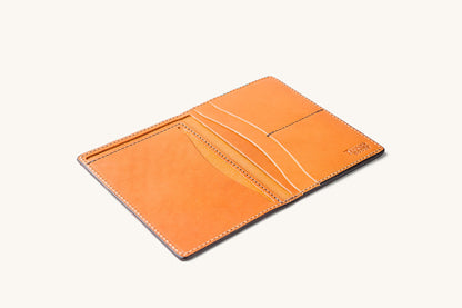 Saddle tan leather travel wallet by Tanner Goods, open to show multiple card slots and stitched edges.