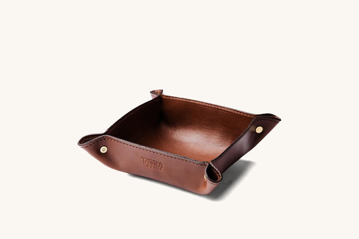 Cognac leather valet tray by Tanner Goods with brass snaps on the upturned corners, angled view.