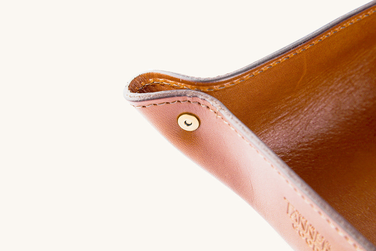 Saddle Tan leather Valet Tray with a gold-colored snap, visible stitching, and partially visible embossed text.